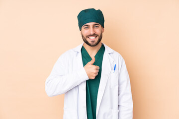 Surgeon man isolated on beige background giving a thumbs up gesture
