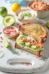 Tasty sandwich with avocado, salmon and dill for fresh lunch.