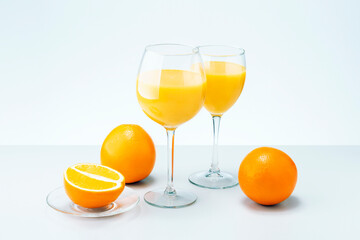 Orange fruit and two glasses of juice on grey surface. Healthy food and drink.