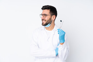 Dentist man holding tools isolated on white background looking to the side