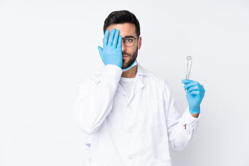 Dentist man holding tools isolated on white background covering a eye by hand