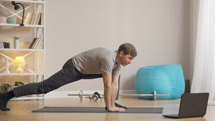 Confident handsome male trainer showing exercise talking at laptop indoors. Portrait of athletic fit middle aged Caucasian man coaching online. Wireless communication and modern sports.