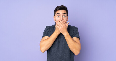 Caucasian handsome man covering mouth with hands over isolated purple background