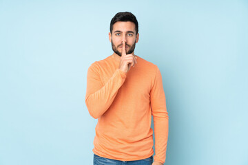 Caucasian handsome man showing a sign of silence gesture putting finger in mouth over isolated blue background