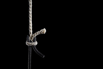 Black and white ropes are tied in a knot on a black background