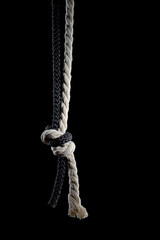 Black and white ropes are tied in a knot on a black background