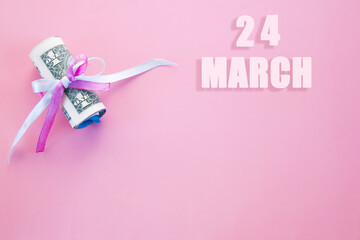calendar date on pink background with rolled up dollar bills pinned by pink and blue ribbon with copy space. March 24 is the twenty-fourth day of the month