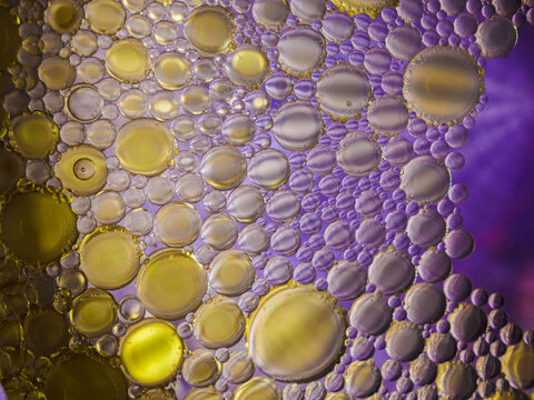 Colorful macro shot of olive oil bubbles in a colored glass of water