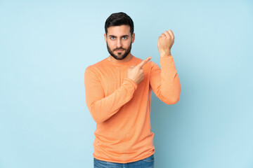 Fototapeta premium Caucasian handsome man making the gesture of being late over isolated blue background