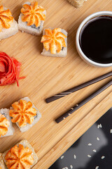 Big sushi set on light wooden dish isolated on black background