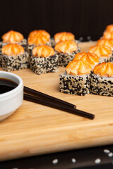 Big sushi set on light wooden dish isolated on black background