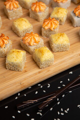 Big sushi set on light wooden dish isolated on black background