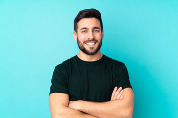 Caucasian handsome man isolated on blue background keeping the arms crossed in frontal position