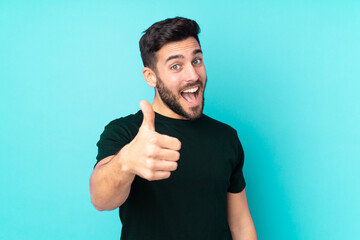 Caucasian handsome man isolated on blue background with thumbs up because something good has...