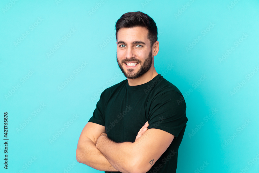 Wall mural Caucasian handsome man isolated on blue background with arms crossed and looking forward