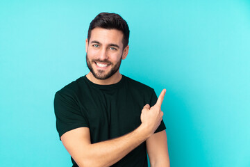 Caucasian handsome man isolated on blue background pointing to the side to present a product