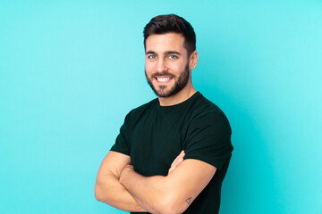 Caucasian handsome man isolated on blue background with arms crossed and looking forward