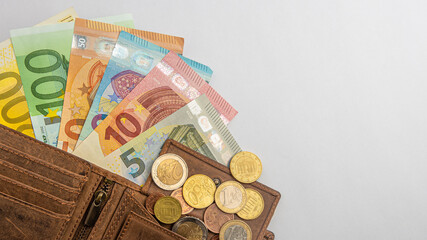 Euromünzen und Banknoten und Porte­mon­naie liegen auf einem wießen Hintergrund mit...