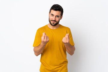 Young handsome man with beard isolated on white background making money gesture but is ruined