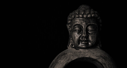 Fototapeta na wymiar Close-up of a meditating Buddha statuette with closed eyes isolated on black background