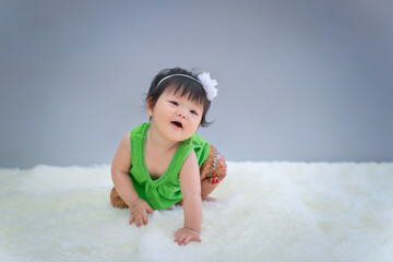 Songkran, Asian baby in Thai costume sit and smile on white carpet. Cute happy 8 months baby sitting with copy space as Songkran festival concept, baby or kid department in hospital