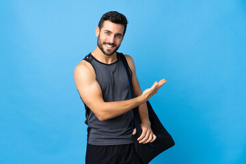 Fototapeta premium Young sport man with sport bag isolated on blue background presenting an idea while looking smiling towards