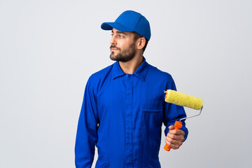 Painter man holding a paint roller isolated on white background looking to the side