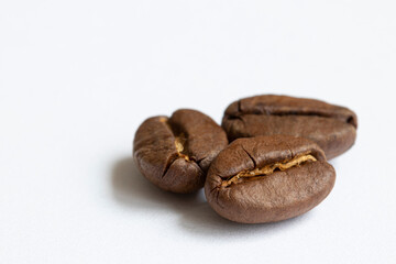 Three grains of aromatic divine coffee on a light background close-up.
