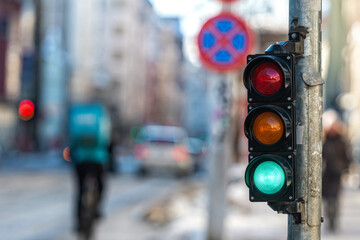 close-up of small traffic semaphore with green light against the backdrop of the city traffic