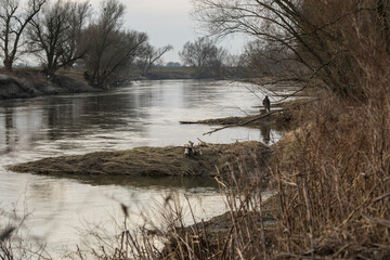 a lonely angler on the bank of a swift large river