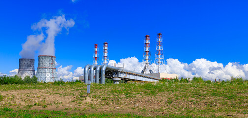 Fototapeta na wymiar thermal power plant on a background of blue sky and green grass