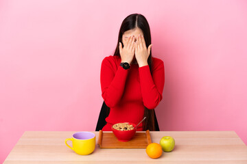 Young Chinese girl  having breakfast in a table with tired and sick expression