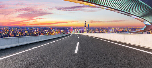 Empty asphalt road and bridge with city skyline at night in Shanghai,China.