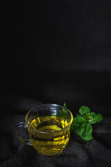 Hot tea in glass cup on natural dark background.