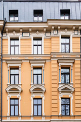 Fototapeta na wymiar Orange brick art nouveau building façade with nine cream windows in Riga, Latvia, Europe