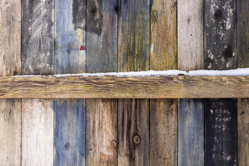 Old aged brown gray blue white black wooden plank fence from inside with snow