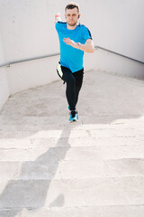 Young man running upstairs on city stairs. Fitness, sport, people, exercising and lifestyle concept