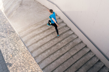 Young man running upstairs on city stairs. Fitness, sport, people, exercising and lifestyle concept
