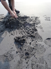creative child making sand sculpture with two hands on the beach design for relaxation lifestyle