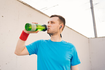 Profile view of sporty young man drinking water from bottle after long city run