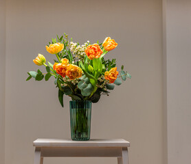 A bouquet of peach and orange colored roses on a small table.