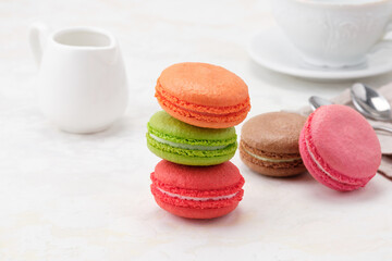 Beatiful colorful Macaroons on a white background. On background with white milkman and a white cup of tea or coffee . Front view.