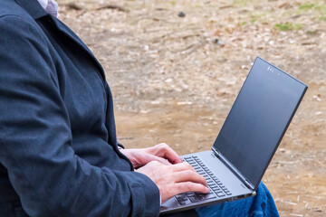 公園でパソコンをタイプする男性