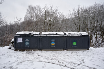 Half underground trash containers in Vilnius covered with wet snow