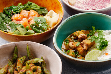 Mix of hawaiiajn salmon poke bowls in colorful bowls with rice and vegetable around