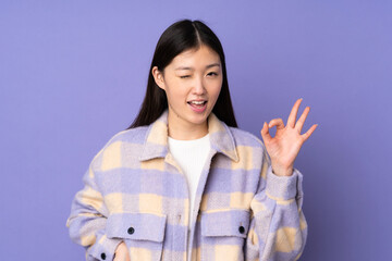 Young asian woman isolated on purple background showing ok sign with fingers