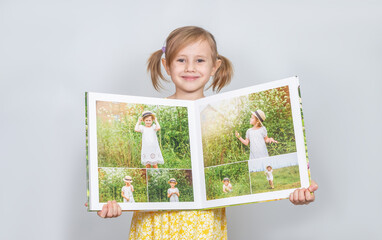 A Little girl holding a photobook with her photographs in her handspt