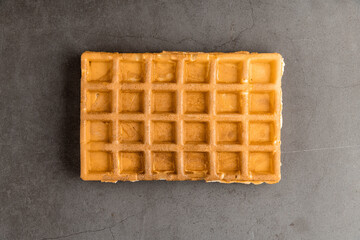 Single Belgian waffle on a dark stone background.