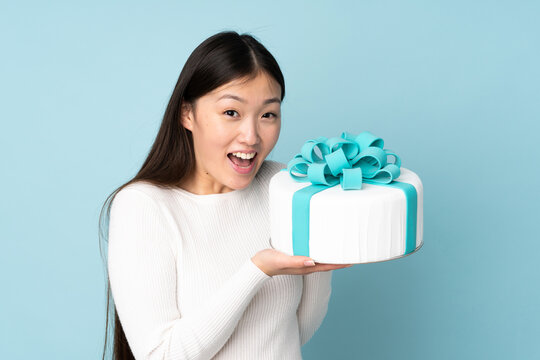 Pastry Asian Chef Holding A Big Cake Isolated On Blue Background