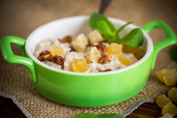 cooked boiled sweet oatmeal with nuts and candied fruits in a bowl